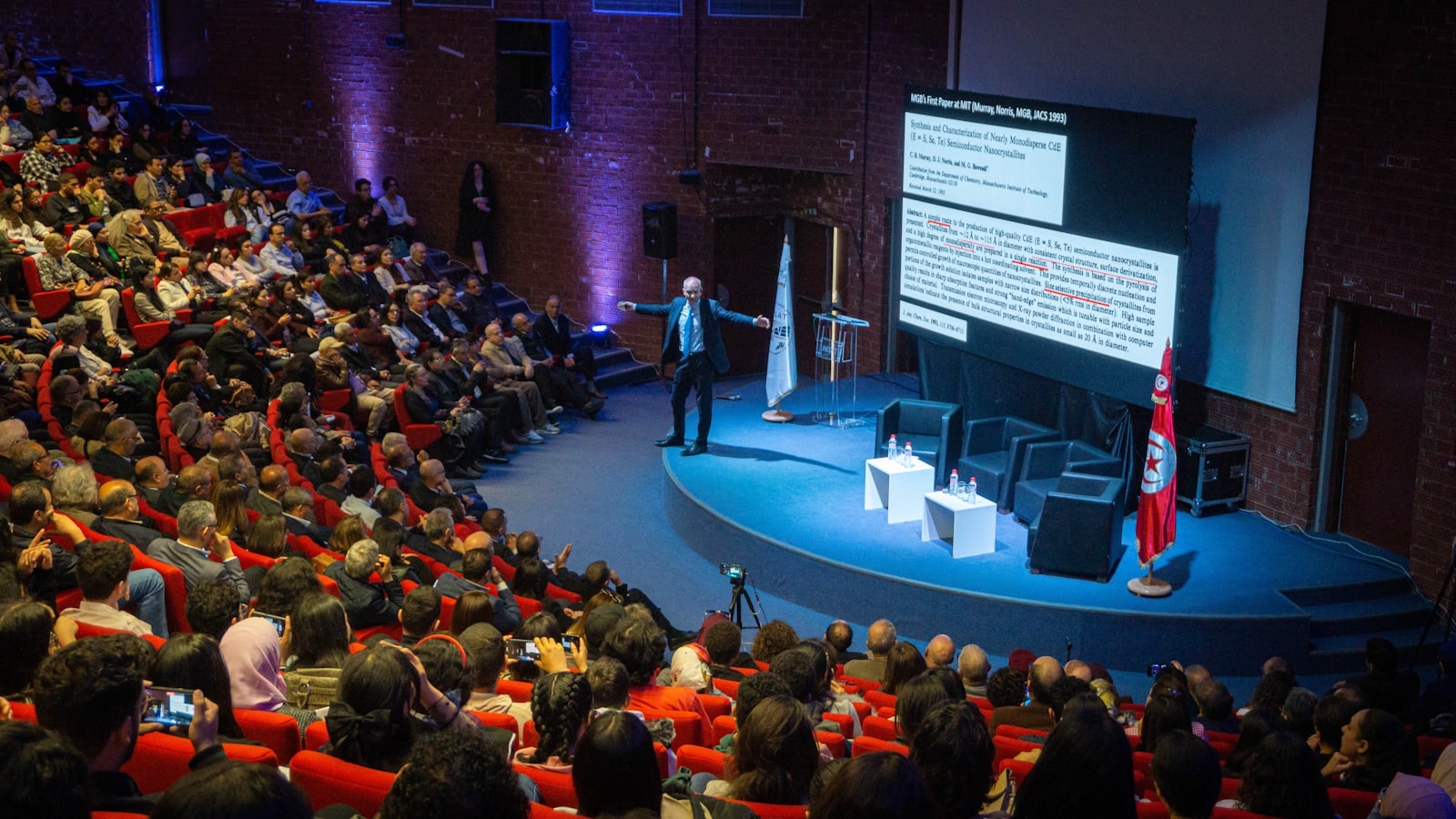 A speaker addressing a full auditorium during a conference session